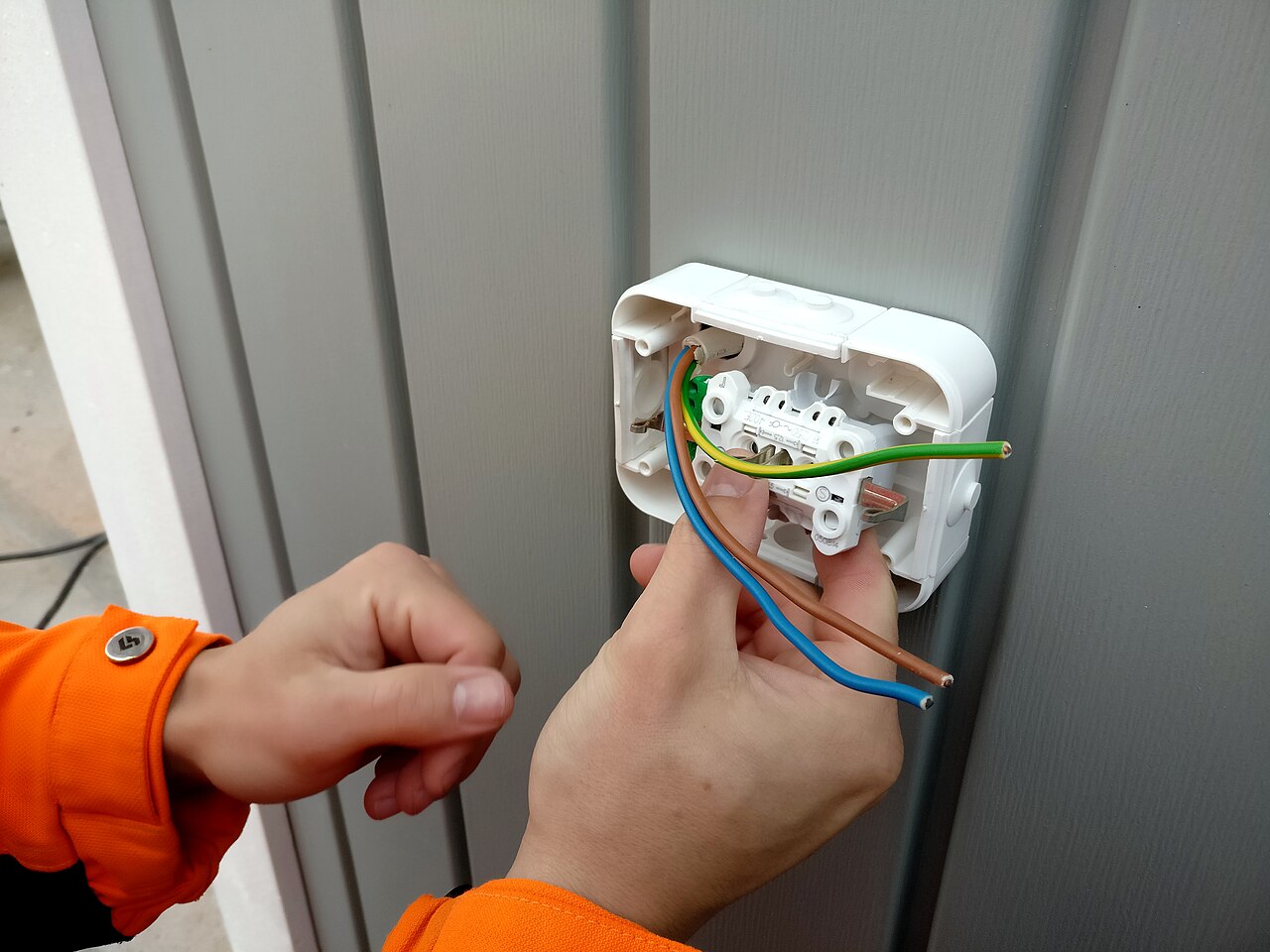 Elektricien sluit de aders van een stopcontact aan op een wandcontactdoos