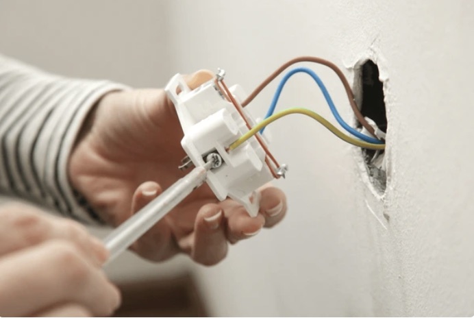 Elektricien monteert een wandcontactdoos in een uitgefreesd wandgat