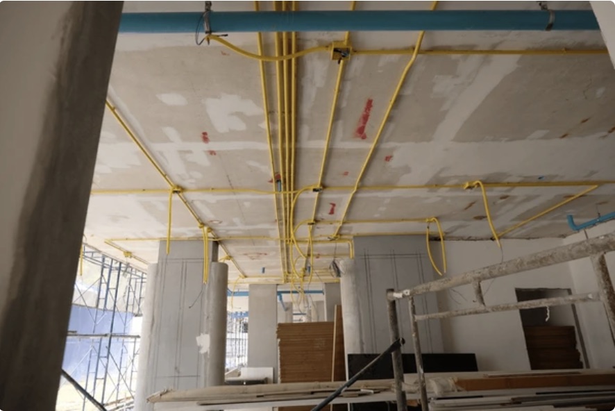 Gele installatiebuizen langs het plafond van een bedrijfspand in aanbouw